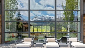 A modern outdoor seating area with a mountain view through large windows. - The Overlook Telluride 5 Bedroom Home (Telluride)