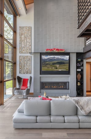 A modern living room with a fireplace, a large flat-screen TV mounted above it, and a grey sofa. - The Overlook Telluride-Includes 2 Ski Passes 5 Bedroom Home (Telluride)