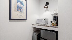 Una kitchenette equipada con microondas, cafetera y un cartel enmarcado en la pared.