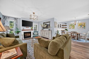 Amplia sala de estar con chimenea, televisor y comedor con mesa y sillas.
