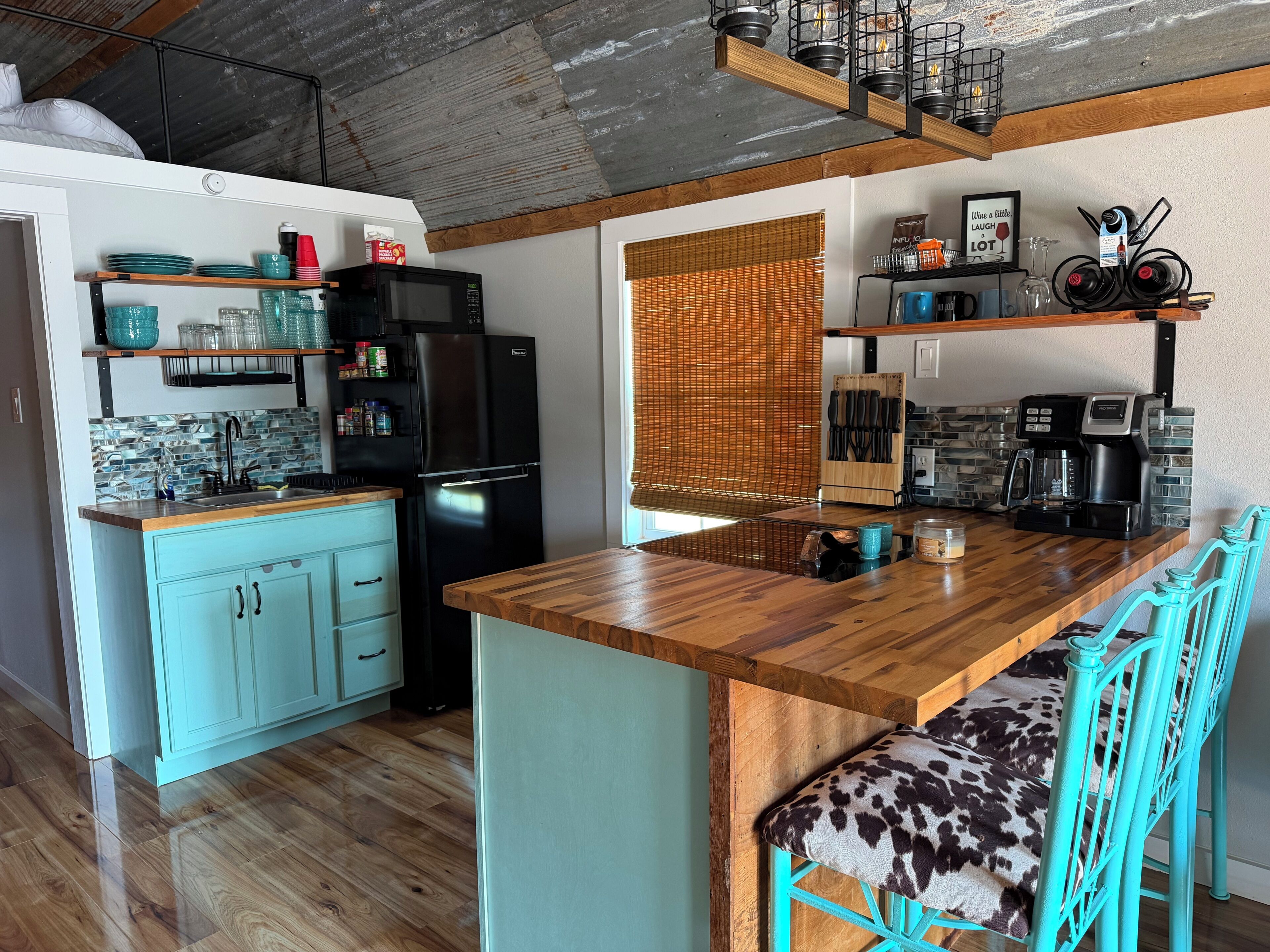 A kitchen with a wooden countertop, a black refrigerator, and a blue cabinet.