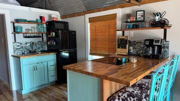 A kitchen with a wooden countertop, a black refrigerator, and a blue cabinet.
