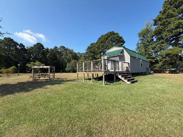 A house with a green roof, a fenced deck, and a grassy yard.