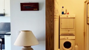A hallway with a wooden table and lamp, a washing machine, and a cabinet. - Quiet house in the city center (Douarnenez)