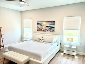 A bedroom with a large bed, bedside tables, a bench, and a ceiling fan. - SunFish - 4-bedroom home in gorgeous Port St. Joe with private in-law suite (Port St. Joe)