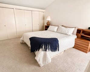 A bedroom with a bed, a nightstand, a lamp, and a wardrobe. - 80`s Oldies Speakeasy Estate - 5 BD - AC (San Diego)