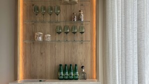 A modern interior with a wooden wall, shelves displaying glassware and bottles, and a round wooden table. - NEW! Caribbean Serenity- Villa Marina Apartment (Maria Chiquita)
