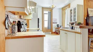 Une cuisine avec des meubles de rangement en bois, un plan de travail et un luminaire suspendu.