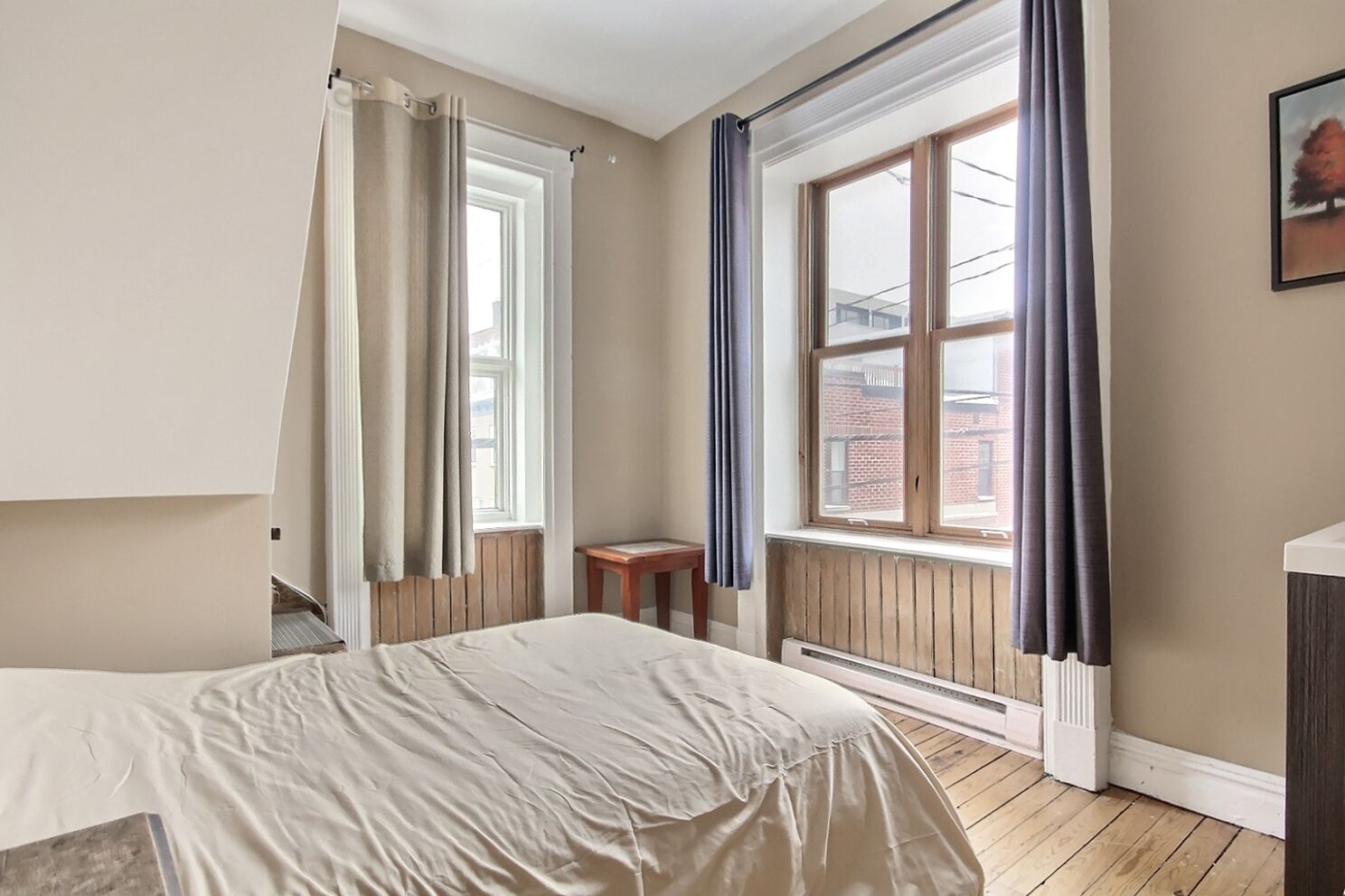 Une chambre avec un lit, une fenêtre, un radiateur et une petite table.