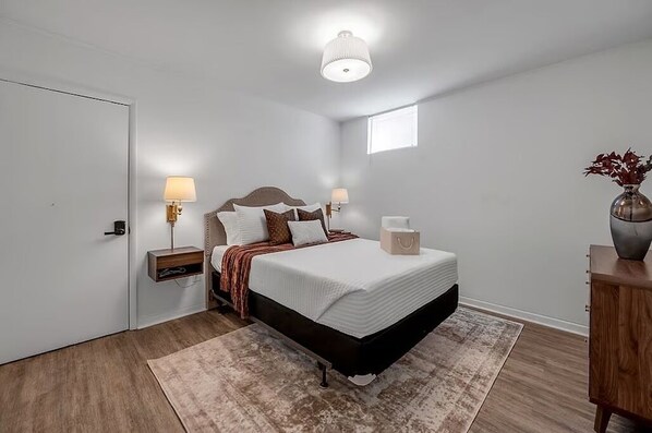 A bedroom with a bed, bedside lamps, a nightstand, a bedside table, a window, and a vase with flowers. - The Mane Stay - 3BR - Walk to Dining - 5 Min to UK (Lexington)
