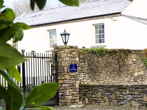 A stone wall with a sign reading 'The Coach House' in front of a white building with a black gate. - Boyne House Slane (Meath)