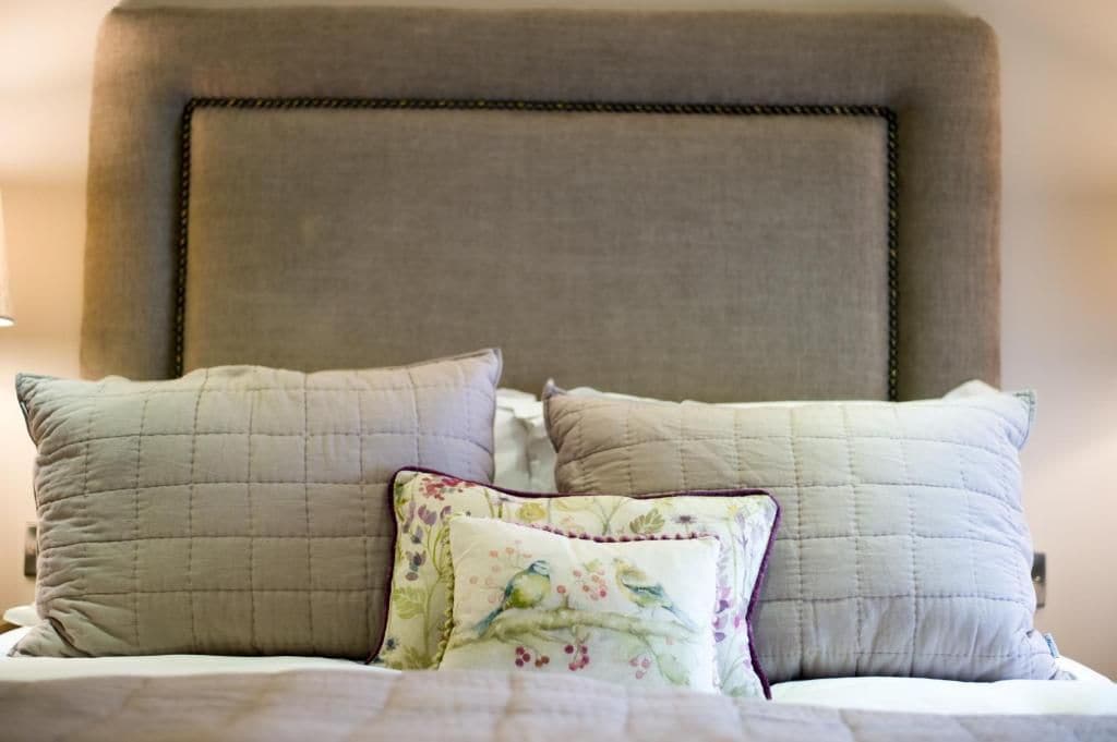A bed with a headboard, multiple pillows, and a floral-patterned pillow.