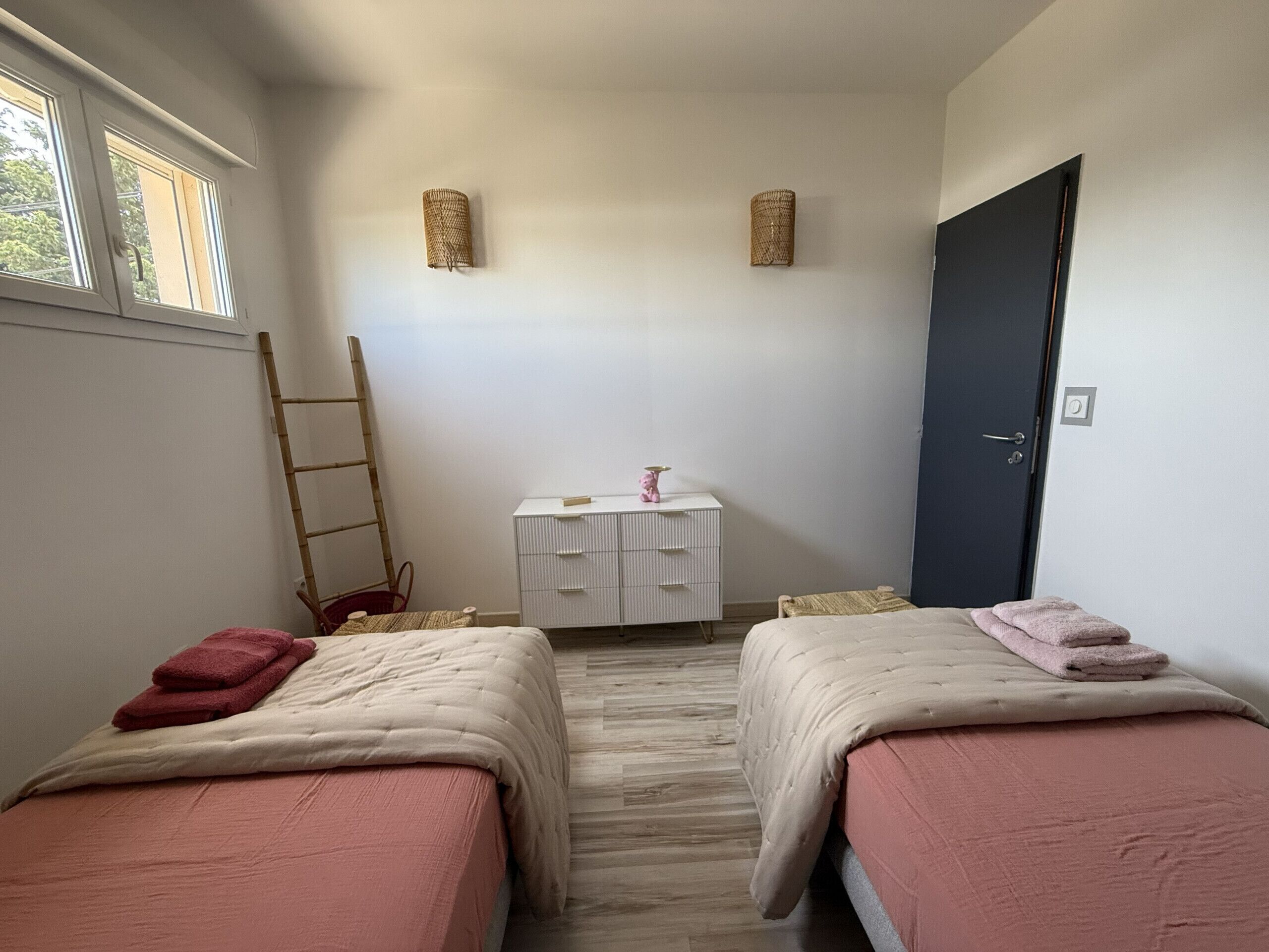 Une pièce avec deux lits, une petite table, une chaise, une échelle et une porte.