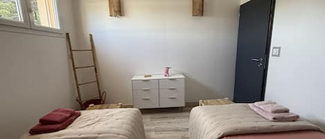 Ett rum med två sängar, ett litet bord, en stol, en stege och en dörr.