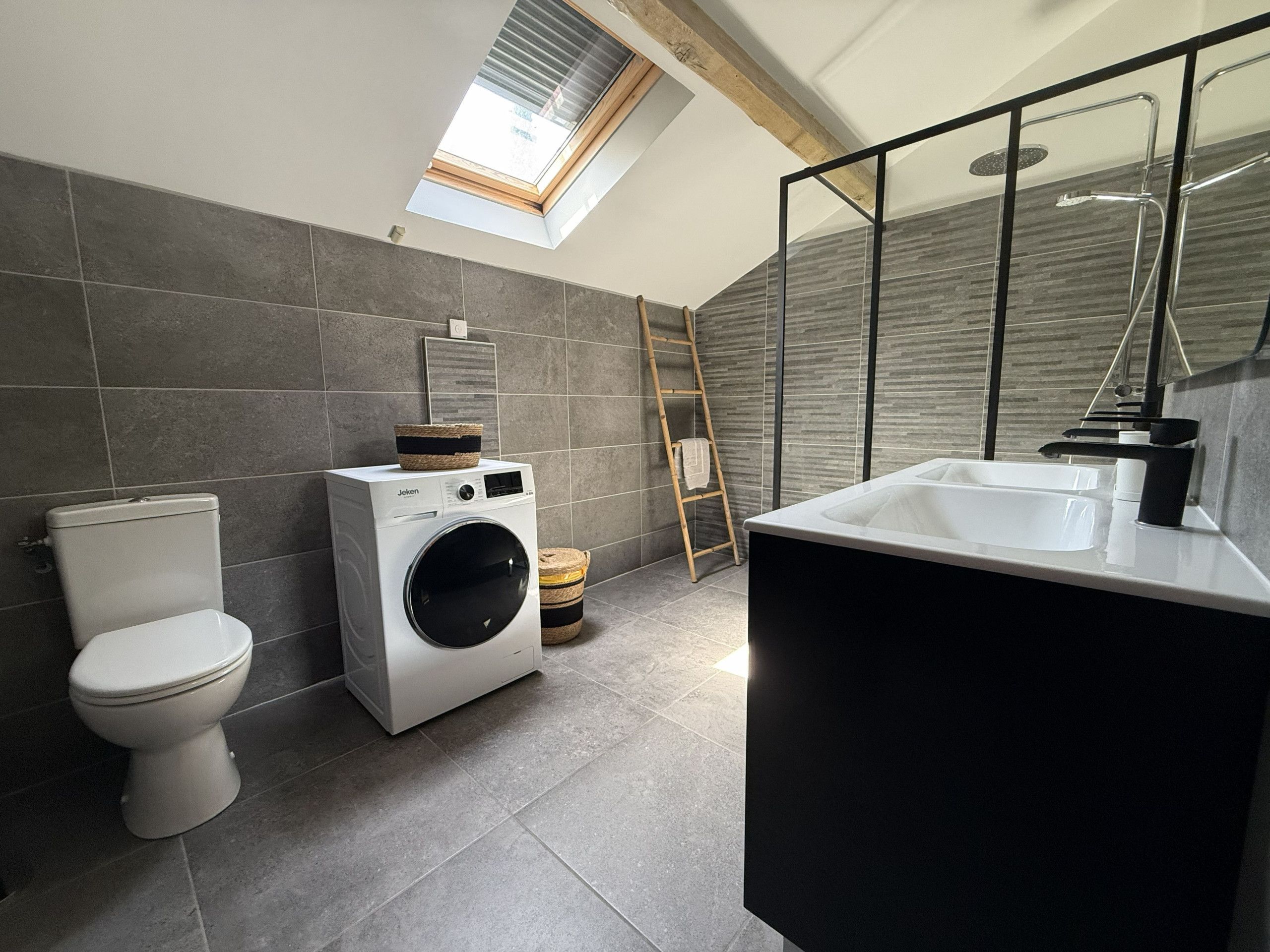 Un baño moderno con tragaluz, lavadora y bañera.
