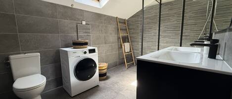 Un baño moderno con tragaluz, lavadora y bañera.