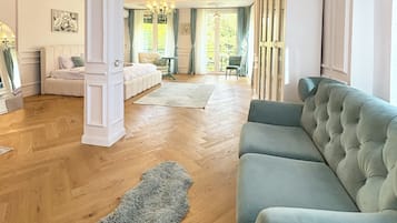 Un salón amplio con un sofá grande de color gris, un sillón blanco y suelo de madera.