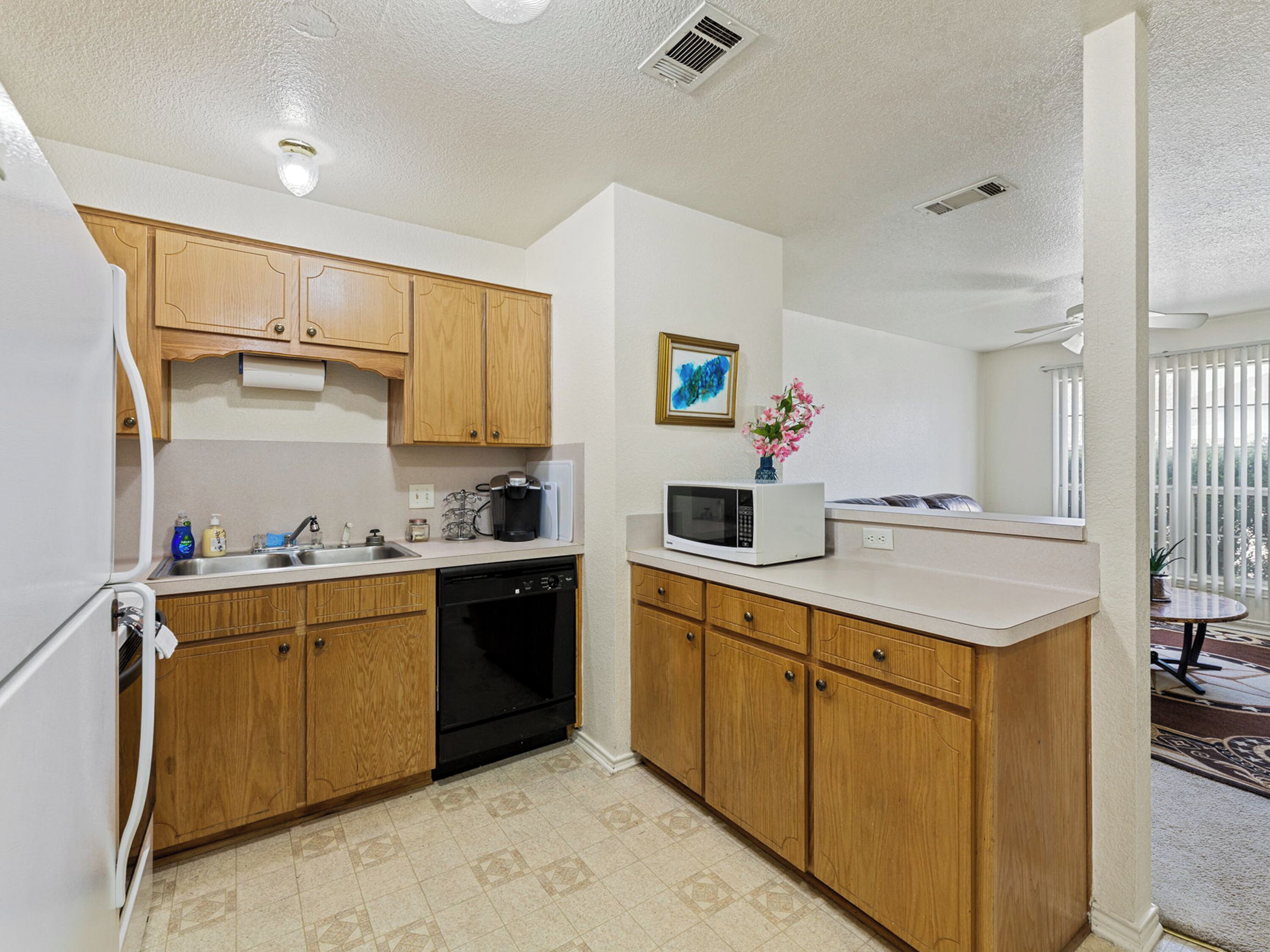 A compact kitchen with wooden cabinets, a dishwasher, a microwave, and a small sink.