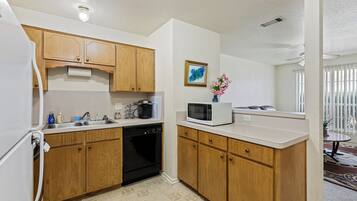 A compact kitchen with wooden cabinets, a dishwasher, a microwave, and a small sink.