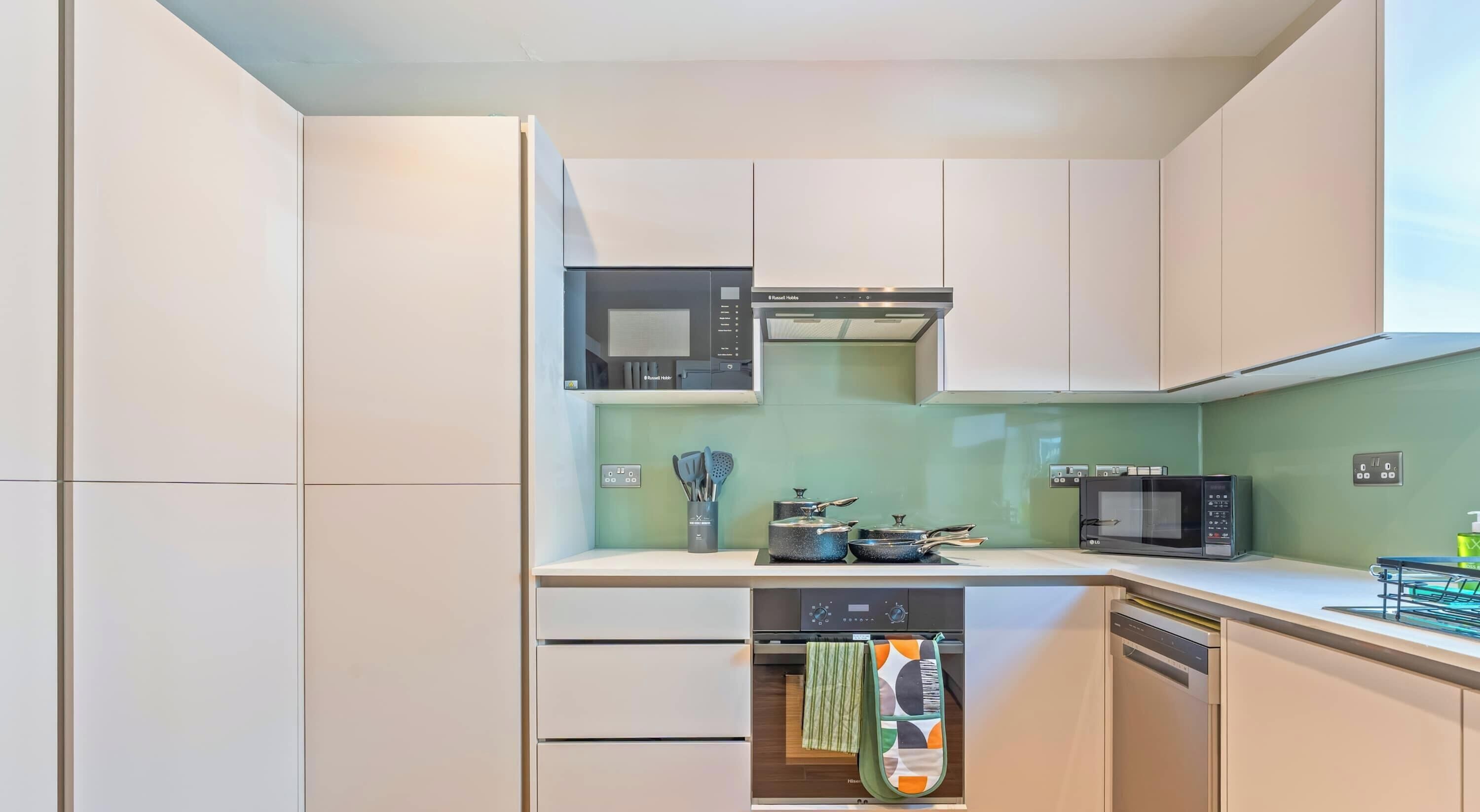 A modern kitchen with white cabinets, a microwave, a stove, and a dishwasher.