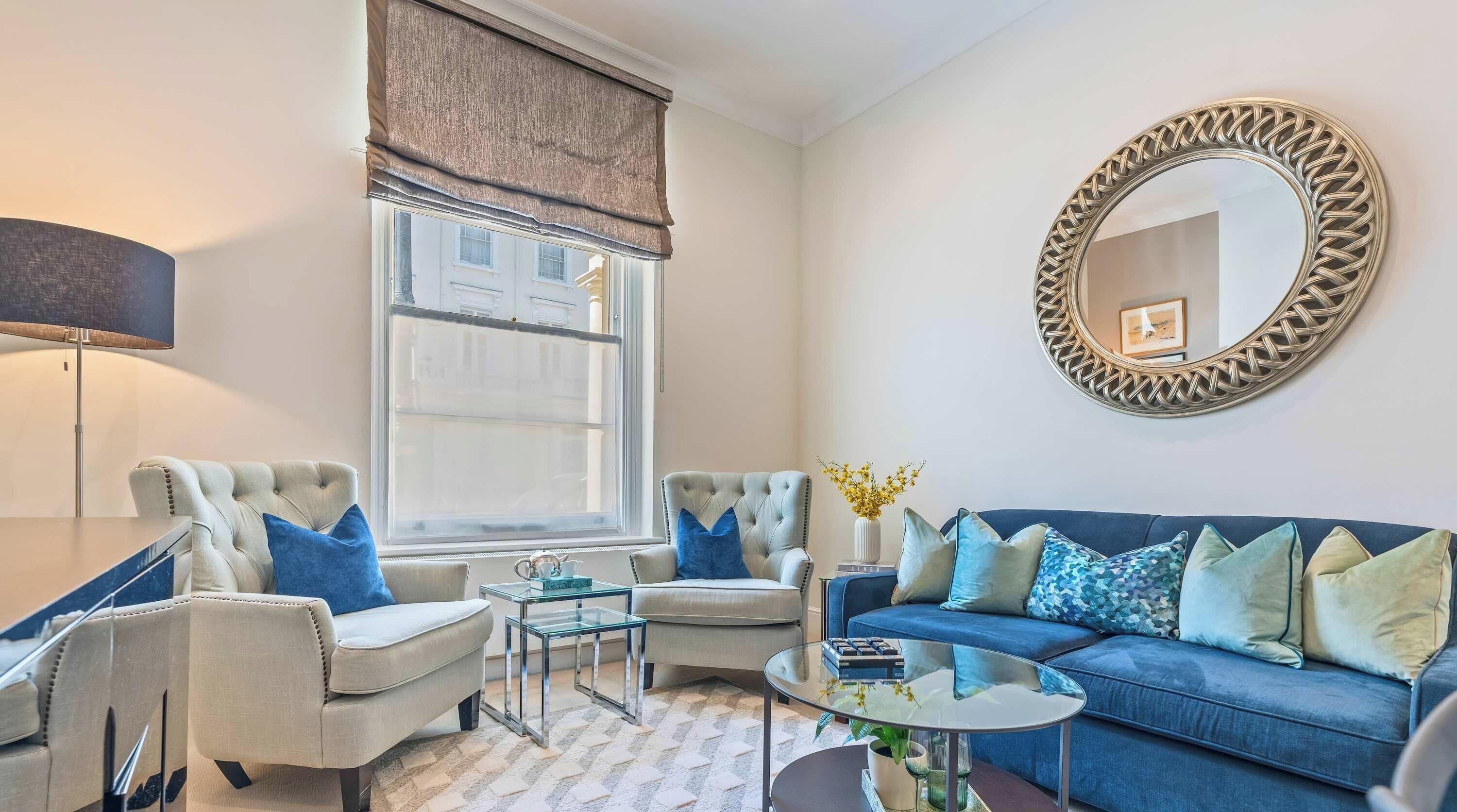 A living room with a sofa, two armchairs, a coffee table, a lamp, and a large mirror.