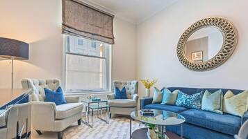 A living room with a sofa, two armchairs, a coffee table, a lamp, and a large mirror.