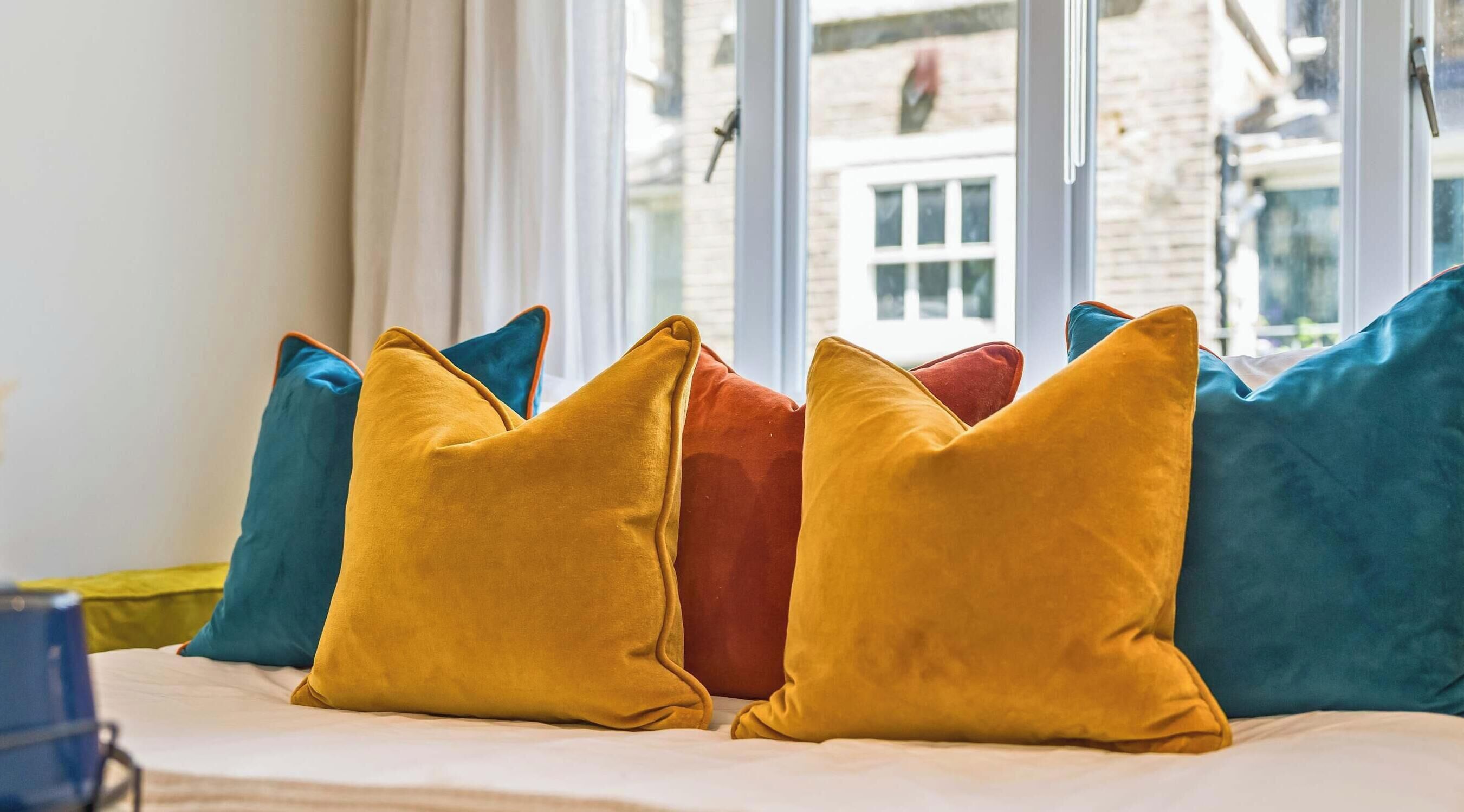 A bed with multiple pillows in various colors.
