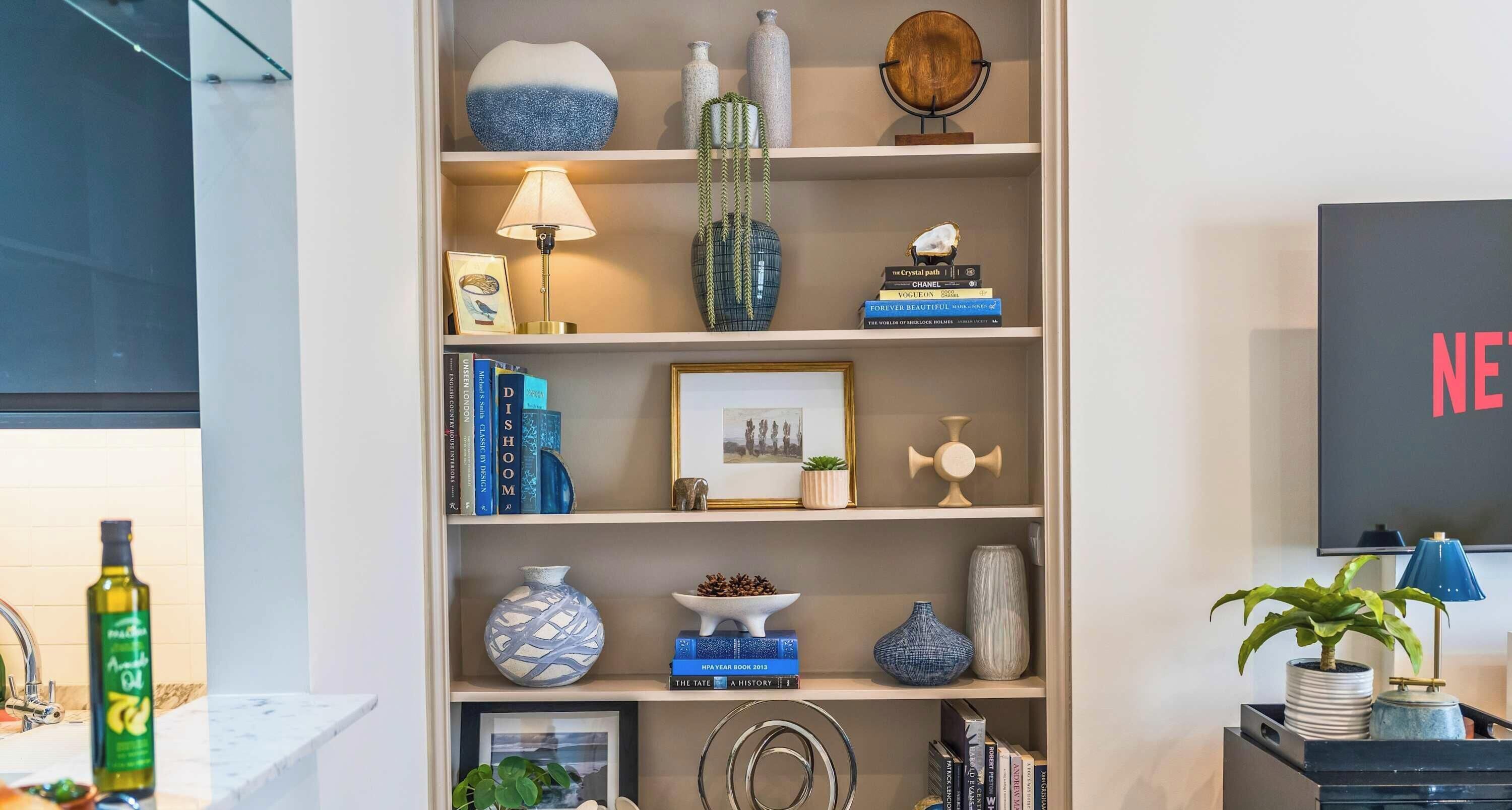 A bookshelf with various decorative items, books, and a framed picture.