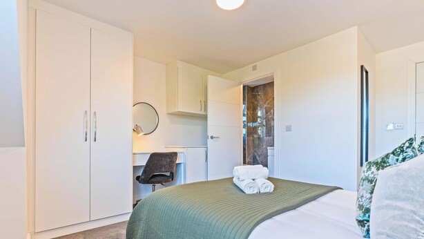 Habitación de hotel con cama, escritorio, silla y armario.