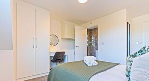 Habitación de hotel con cama, escritorio, silla y armario.