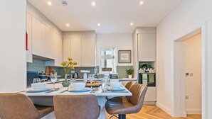 Una cocina moderna con comedor, equipada con estufa, lavaplatos y refrigerador.