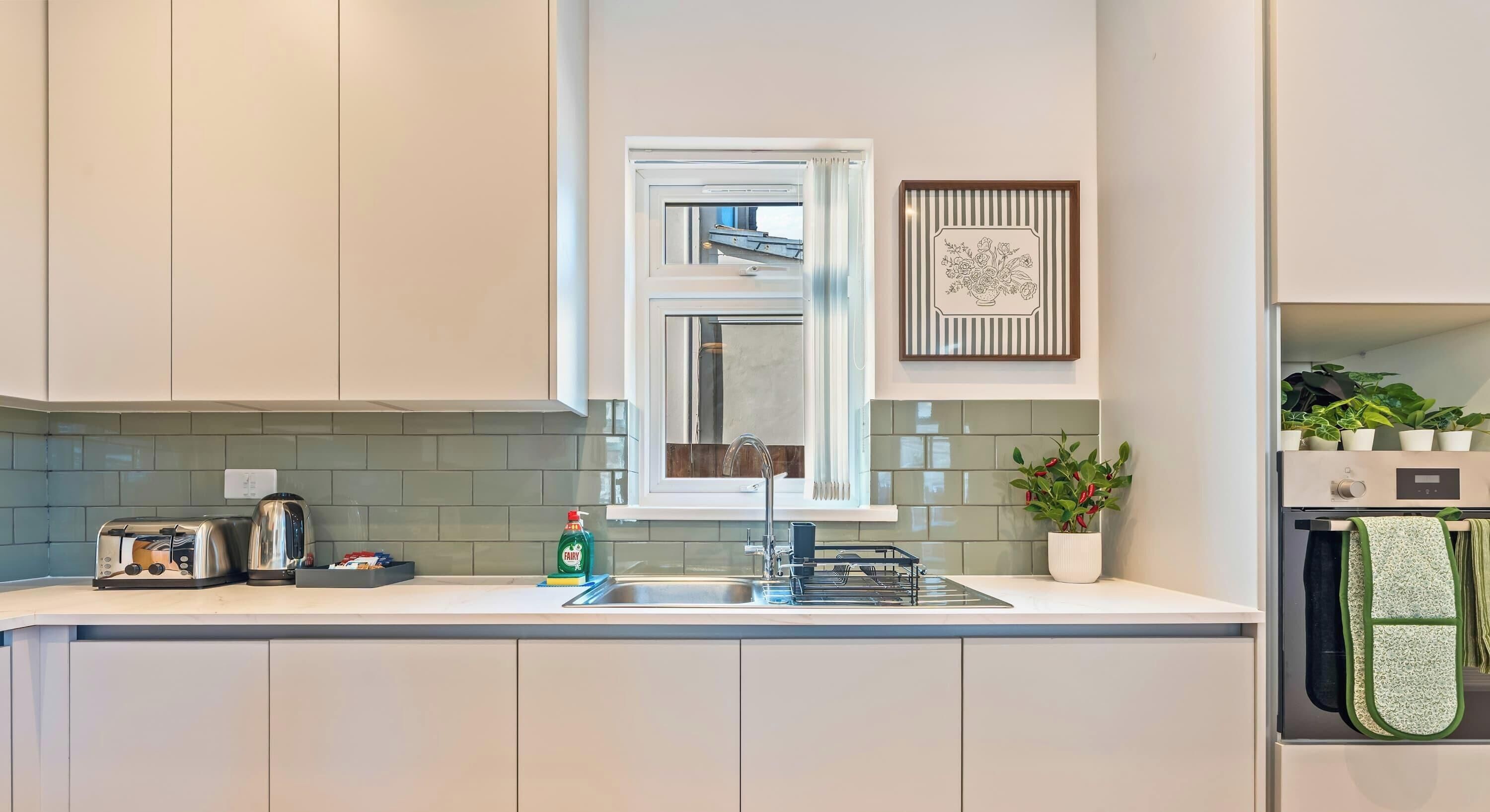 A modern kitchen with a built-in stove, a sink, and a window above the counter.