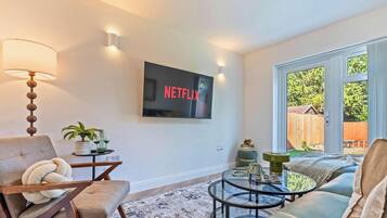 A living room with a flat-screen TV mounted on the wall, a sofa, a coffee table, and a lamp.