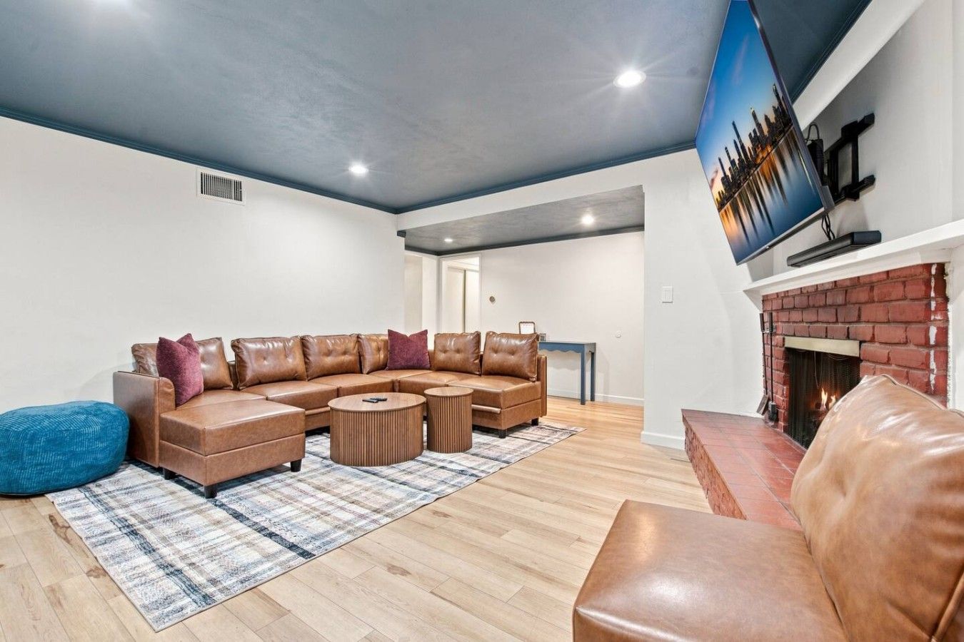 Una sala moderna con un sofá modular, una chimenea y un televisor montado.