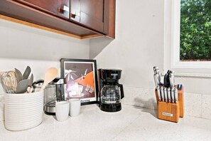 Una encimera de cocina con una cafetera, utensilios y un marco con una fotografía.