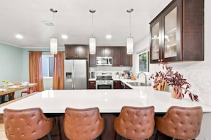 A modern kitchen with a central island, stainless steel appliances, and pendant lighting. - SDSU Splash Royale 6BR| 12 Bed | Pool&Spa | GameRm (San Diego)