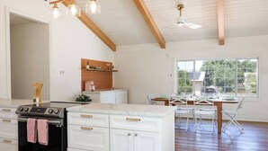 A kitchen with a central island, white cabinetry, a black oven, and a dining area with a table and chairs. - 6BR SDSU - Pool & Spa - Poker/Game Rm - Sleep 20+ (San Diego)