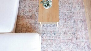 A room with a patterned rug, a wooden coffee table with a plant, a green armchair, and a white sofa. - 6BR SDSU - Pool & Spa - Poker/Game Rm - Sleep 20+ (San Diego)