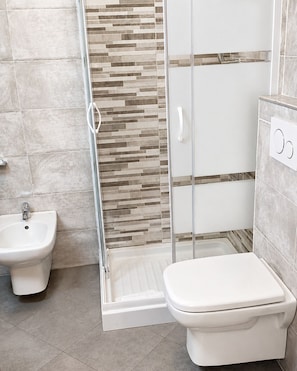 A bathroom with a bidet, toilet, and glass shower enclosure. - Hotiday Firenze Novoli (Florence)