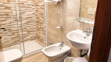 Un baño moderno con ducha, bidé y dos lavamanos.