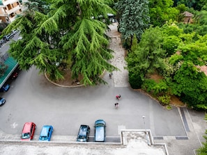 An aerial view of a parking area with several cars, a stone pathway, and surrounding greenery. - Hotiday Firenze Novoli (Florence)