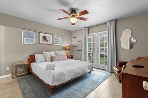 A bedroom with a bed, bedside tables, a ceiling fan, and a view of the outdoors through a window. - New! Denver House Near Pearl St & Wash Park | Patio | Fire Pit | Fenced Yard (Denver)