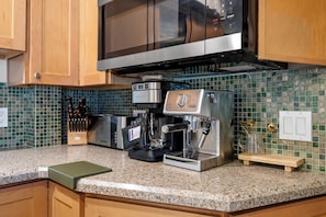 A kitchen with a coffee machine, microwave, and tiled backsplash. - New! Denver House Near Pearl St & Wash Park | Patio | Fire Pit | Fenced Yard (Denver)