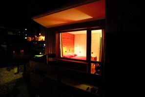 Una habitación con cama, mesita de noche y ventana con cortinas.