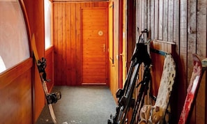 Ein Holzboden-Flur mit einer Tür, auf der '15' steht, und Skiern, die an der Wand lehnen.