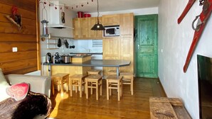 A cozy living area with a sofa, a dining table with chairs, a kitchen with wooden cabinets, and a green door. - Very comfortable apartment in Belle-Plagne, 50 m² (La Plagne Tarentaise)