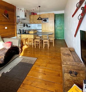 A cozy living area with a sofa, a dining table with chairs, a kitchen with wooden cabinets, and a green door. - Very comfortable apartment in Belle-Plagne, 50 m² (La Plagne Tarentaise)