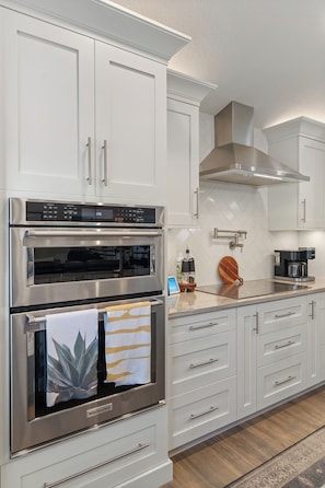 A modern kitchen with stainless steel appliances, white cabinetry, and a wooden cutting board on the countertop. - Waterfront 4BR/2.5BA home with direct access to the Clermont Chain of Lakes! Private dock with boat slips & 1 motorized lift — perfect for boating & kayaking.  Gourmet kitchen, luxurious primary suite, available kayaks onsite. (Clermont)