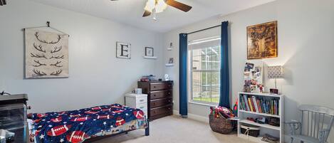 A child's bedroom with a bed, dresser, bookshelf, and a ceiling fan.