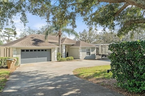 A two-story house with a garage, a covered patio, and a well-maintained lawn. - Waterfront 4BR/2.5BA home with direct access to the Clermont Chain of Lakes! Private dock with boat slips & 1 motorized lift — perfect for boating & kayaking.  Gourmet kitchen, luxurious primary suite, available kayaks onsite. (Clermont)
